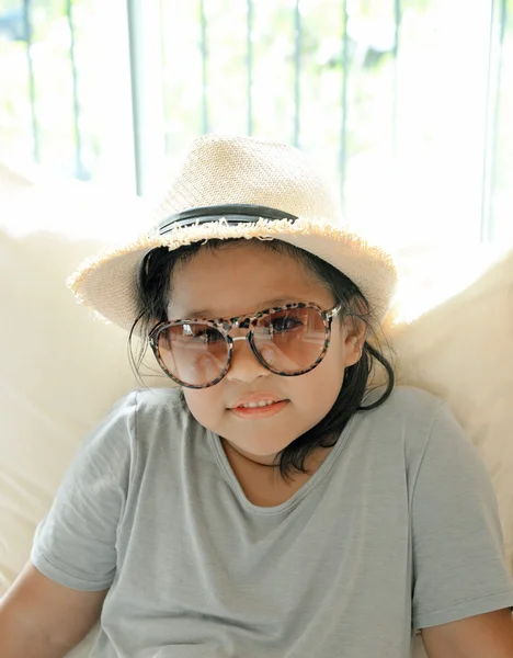 Schönes lächelndes kleines Mädchen mit Brille sitzt im Wohnzimmer. (entspannen) — Stockfoto