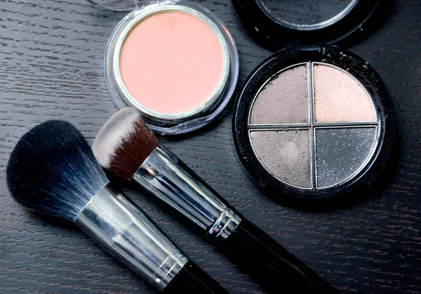 Produtos cosméticos de maquiagem em fundo preto de madeira — Fotografia de Stock