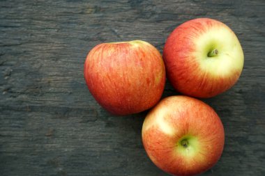 Ahşap arka plan üzerinde üç kırmızı elma