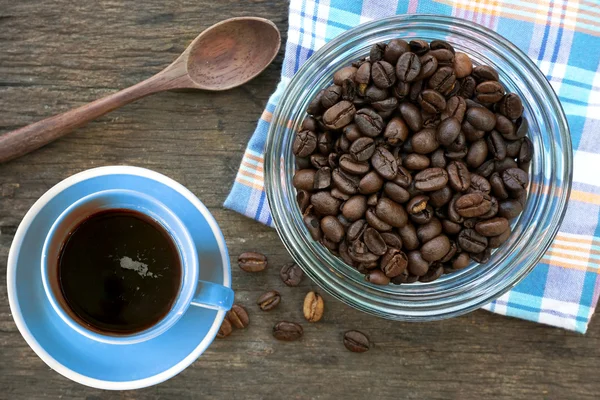 Grains de café arabica torréfiés noirs et tasse pleine de café — Photo