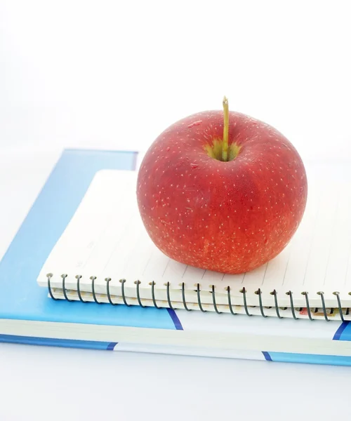 Roter Apfel sitzt auf einem geöffneten Notizbuch — Stockfoto