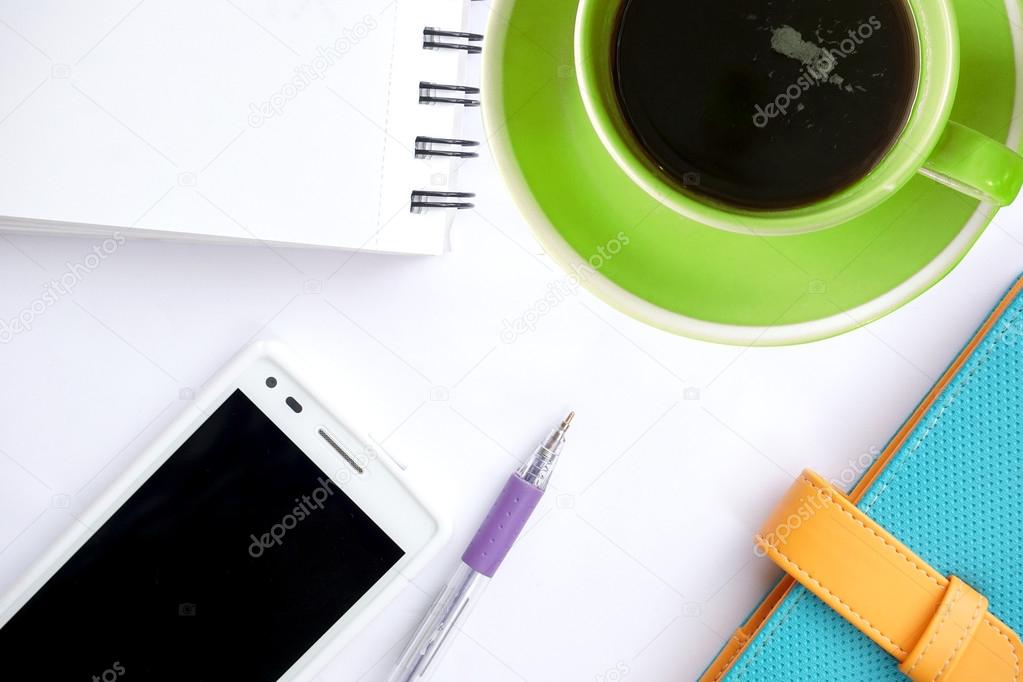 Green coffee cup and office supplies. View from above. Closeup on white background