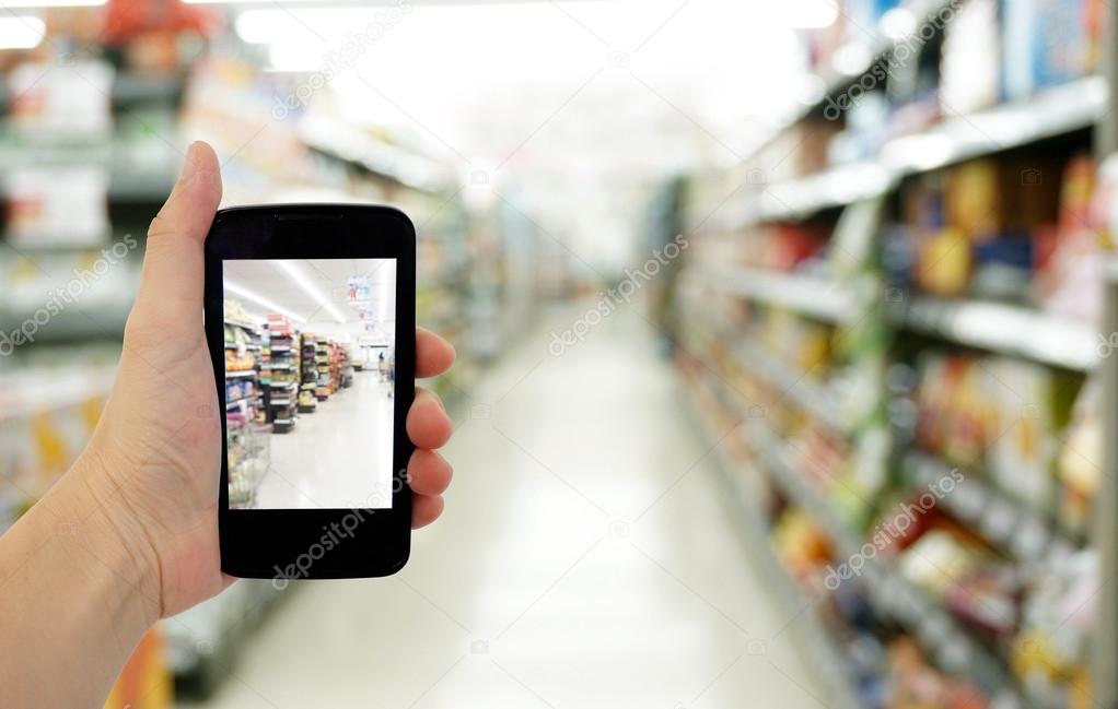 Hand hold smartphone in supermarket