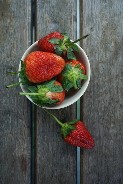 Fresas rojas maduras frescas en tazón sobre tabla texturizada de madera vista superior —  Fotos de Stock