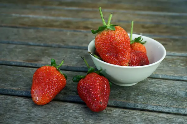 Fresas frescas en un tazón sobre una mesa de madera —  Fotos de Stock