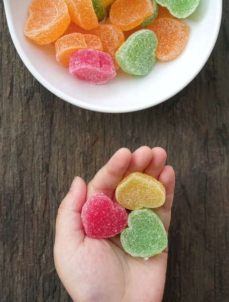 Child hands full of colorful jelly candies with sugar