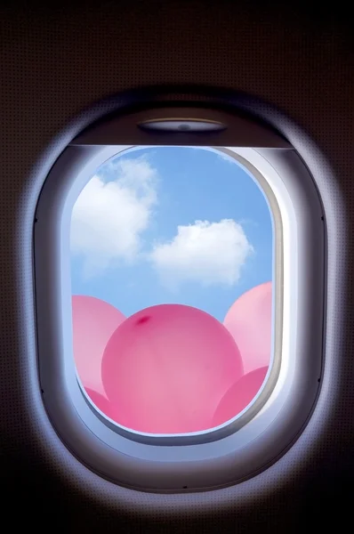 Nuages et ballons roses dans le hublot de l'avion — Photo