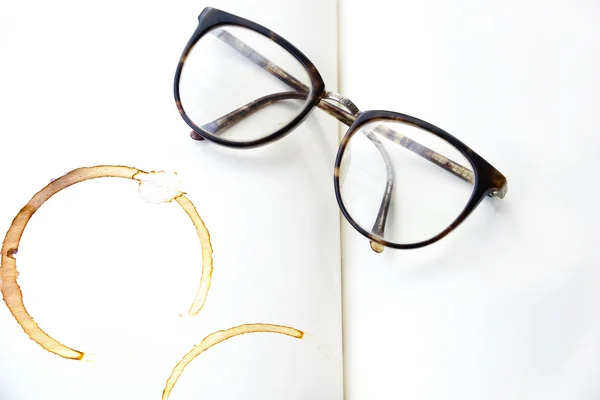 Lunettes sur le livre ouvert, avec impression tasse de café . — Photo