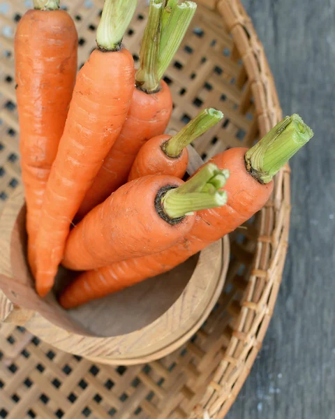 Φρέσκα βιολογικά καρότα σε ένα καλάθι σε φόντο ξύλινη — Φωτογραφία Αρχείου
