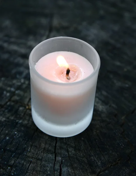 Burning candle on old wooden table — Stock Photo, Image