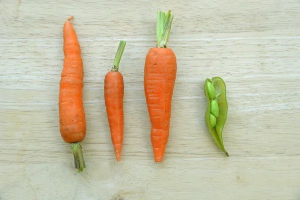 Carrots and peas on wooden background. — Stock Photo, Image