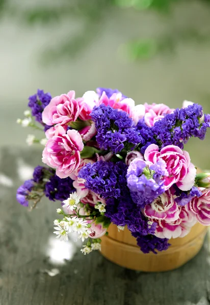 Balde com flores silvestres no banco ao ar livre — Fotografia de Stock