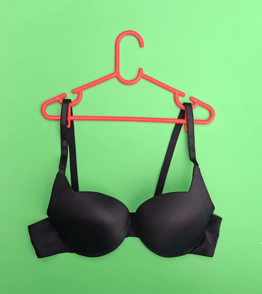 Bra on hanger on green background — Stock Photo, Image