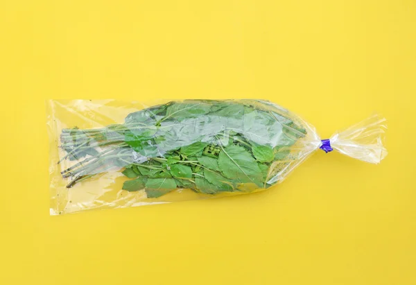 Sweet basil in plastic bag on yellow background (Pop art style) — Stock Photo, Image