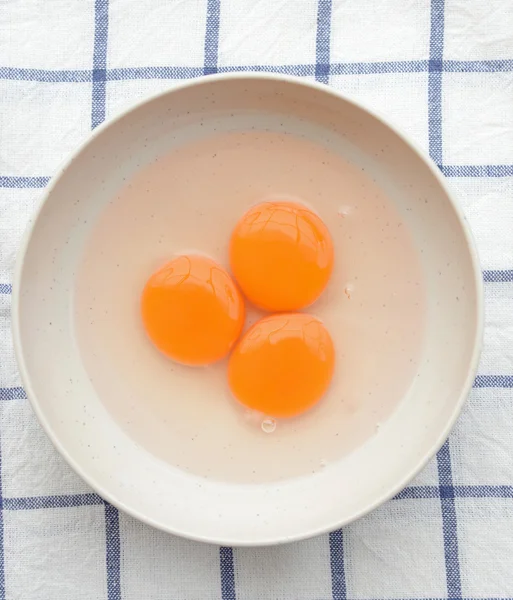 Three yellow egg yolks in white bowl (top view) — Stock Photo, Image