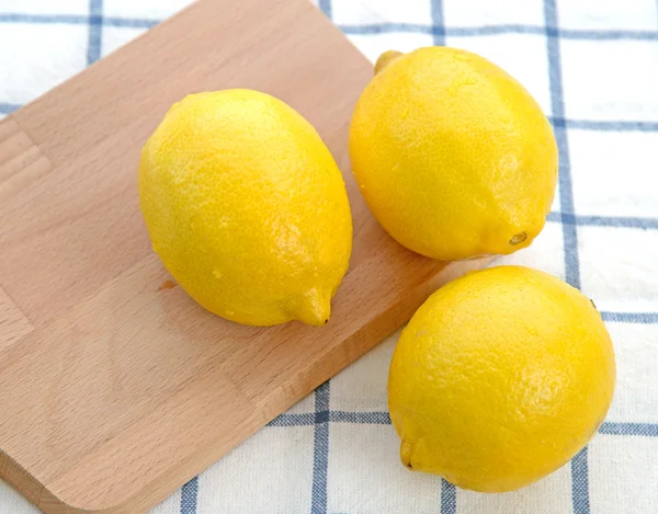 Три лимона на деревянной тарелке — стоковое фото
