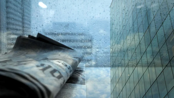 Газета у окна офиса с дождём на улице — стоковое фото