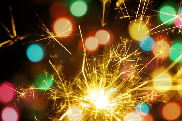 Bengala fuego, chispeante y colorido bokeh navidad, año nuevo fondo . — Foto de Stock