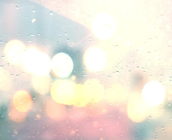 Droppar regn på glas bakgrund. Gatubokeh ljus ur fokus. — Stockfoto
