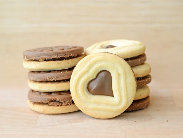 Choklad fyllda kakor i hjärta form på träplatta. — Stockfoto