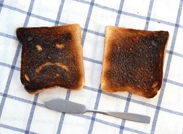 Sad and unhappy smiley made from toasted bread with knife — Stock Photo, Image