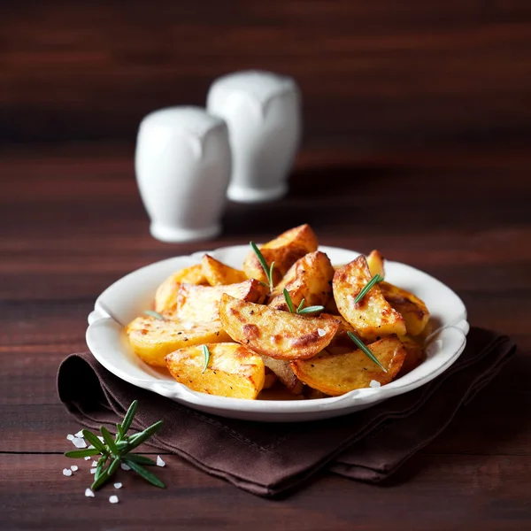 Roasted potato wedges with rosemary on plate — Stock Photo, Image