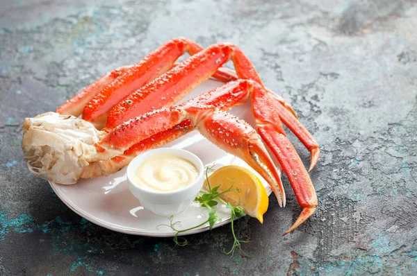 stock image Crab legs with sauce and lemon on a plate, selective focus