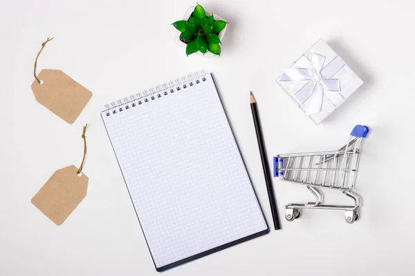 Laptop, note book and shopping trolley on a white background. Online shopping concept