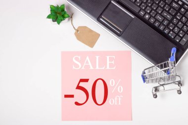 Kara Cuma. Dizüstü bilgisayar, not defteri ve beyaz arka planda alışveriş arabası. Çevrimiçi alışveriş kavramı