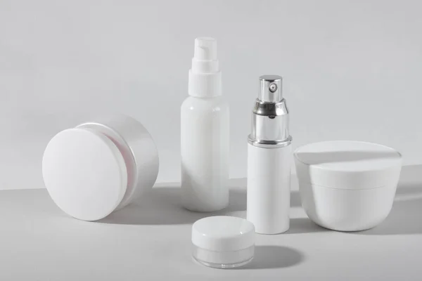 Set of white cosmetic bottles and jars with hard shadows. Home and beauty salon care concept