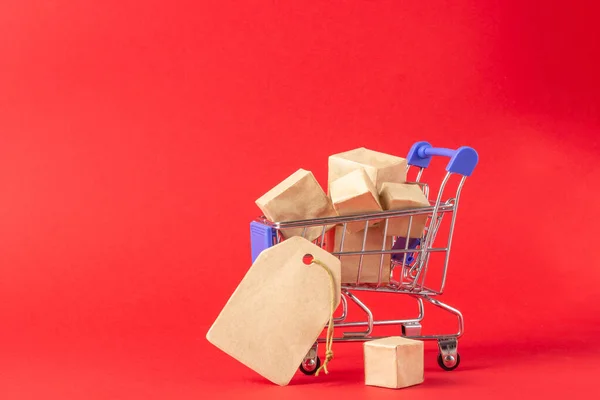 Varukorg och lådor med köp med plats för att lägga till text på en röd bakgrund. Koncept för e-handel — Stockfoto