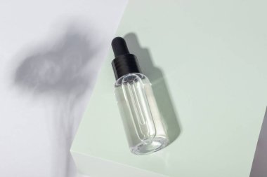 Podyumda sert gölgeli bir kozmetik cam şişesi. Güzellik salonu ve doğal kozmetik ürünleri konsepti.