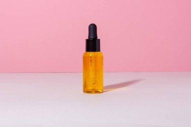 Arka planda gölgeler olan serum şişesi. Cilt bakım ürünleri ve pipette.