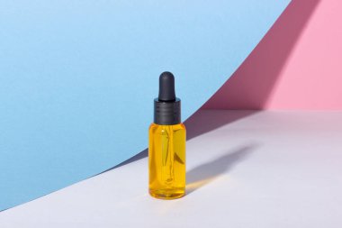 Arka planda gölgeler olan serum şişesi. Cilt bakım ürünleri ve pipette.