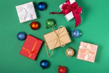 Parlak hediye kutuları ve Noel süslemeleri, yeşil arka planda. Üst görünüm, tatil ve Noel konsepti.