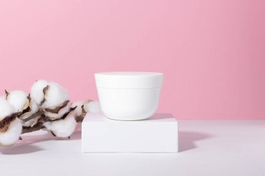 Doğal kozmetik. Kremalı ya da maskeli kavanoz. Kürsüde kadın derisi bakım ürünleri olan beyaz konteynır. Güzellik salonu ve doğal kozmetik ürünleri konsepti.