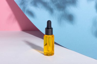 Arka planda gölgeler olan serum şişesi. Cilt bakım ürünleri ve pipette.