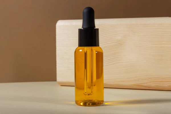 Een glazen cosmetische fles met een druppelaar op een beige achtergrond in fel zonlicht. Het concept van natuurlijke cosmetica, natuurlijke essentiële olie. — Stockfoto