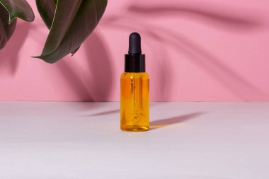 Arka planda gölgeler olan serum şişesi. Cilt bakım ürünleri ve pipette.