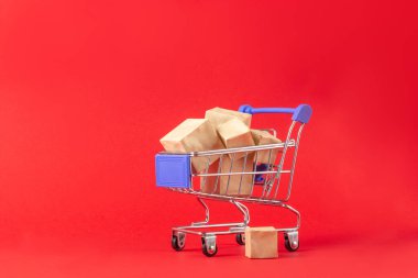 Alışveriş sepeti ve kırmızı arka planda metin eklemek için yeri olan kutular. Çevrimiçi alışveriş ve satış kavramı