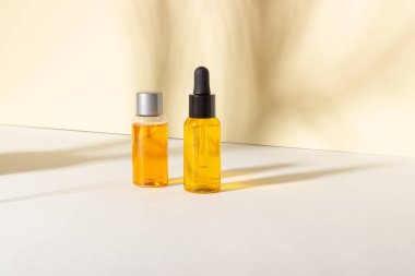 Serum ve esaslı kozmetik yağ şişesi. Arka planda gölgeler var. Cilt bakım ürünleri ve pipette.