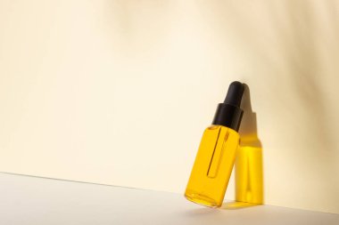 Serum ve esaslı kozmetik yağ şişesi. Arka planda gölgeler var. Cilt bakım ürünleri ve pipette.
