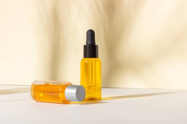 Serum ve esaslı kozmetik yağ şişesi. Arka planda gölgeler var. Cilt bakım ürünleri ve pipette.