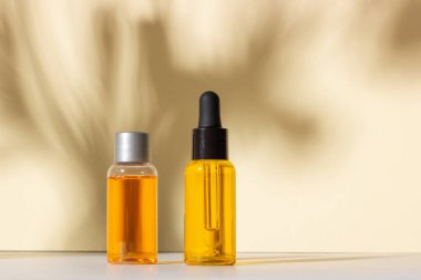 Serum ve esaslı kozmetik yağ şişesi. Arka planda gölgeler var. Cilt bakım ürünleri ve pipette.