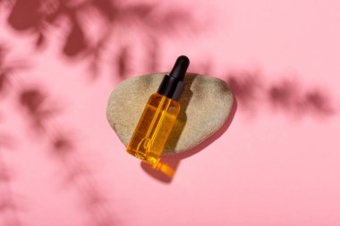 Serum şişesi, arka planda gölgeler olan temel kozmetik yağı. Kozmetik spa ürünü ve pipette. Bronzlaşma yağı