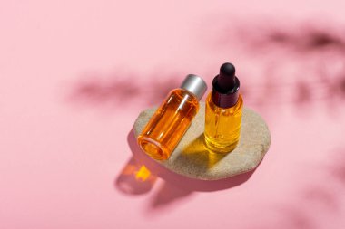 Serum şişesi, arka planda gölgeler olan temel kozmetik yağı. Kozmetik spa ürünü ve pipette. Bronzlaşma yağı