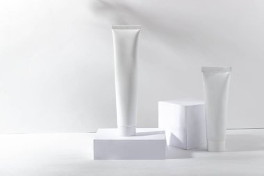 Beyaz kozmetik kavanozu gölgeli bir stantta. Diş macunu, yüz ve vücut kremi. Cilt bakımı için profesyonel kozmetik. Organik Kozmetik.