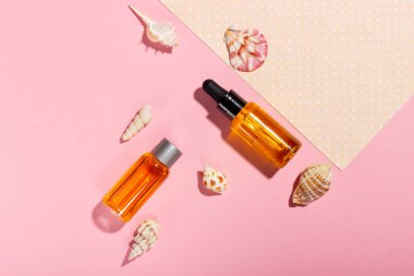 Bronzlaşma yağı. Kozmetik ürünleri deniz kabuklarının yanında pembe bir arka planda güneş ışınları içinde. Güneş koruyucu kozmetikler.