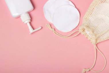 Pamuk çıkarılabilir makyaj pedleri bir bez torba içinde ve yüz yıkama ve pembe arka planda temizleyici. Ekoloji ve bilinçli tüketim kavramı. Yeniden kullanılabilir pamuk pedleri