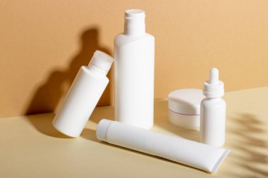 Yüz ve vücut bakımı için kadın profesyonel kozmetik seti. Bej arka planda cilt bakımı ürünü ve sert gölgeli kozmetik tüp.